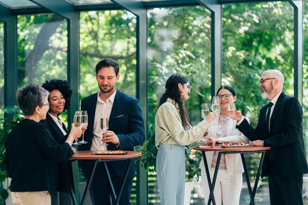 men and women in business suits standing at tables with cocktails